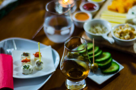 Glass of whisky single malt and set with different appetizers in small portions, delicious snacks and drinkの写真素材