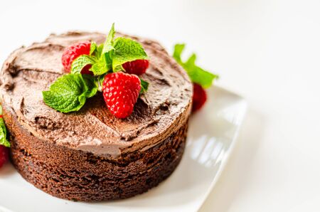Gluten free tasty round cake based on Belgian chocolate decorated with fresh raspberries and mint, delicious sweetsの写真素材
