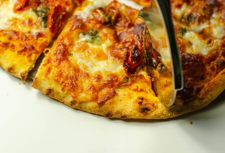 Cutting famous Neapolitan pizza based on buffalo mozzarella and tomatoes with a pizza cutter, italian cuisineの写真素材