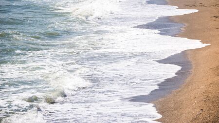 Close up of the sea water affecting the sand on the beach, sea waves calmly flowing sand, relaxing view, summer timeの写真素材