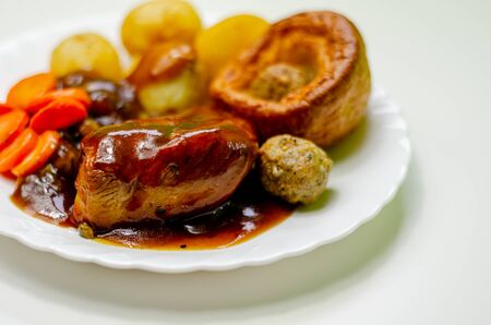 Roast potatoes and roast chicken breast in a chicken and white wine gravy with peas, carrots, pork and onion stuffing and a Yorkshire pudding, traditional english foodの写真素材