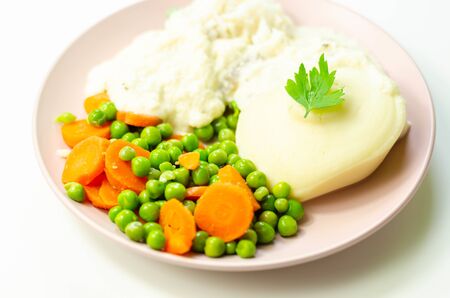 Cod fillet with a creamy cheese sauce, with mashed potato, peas and carrots, traditional british mealの写真素材