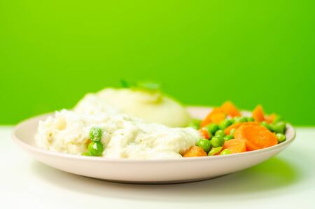 Cod fillet with a creamy cheese sauce, with mashed potato, peas and carrots, traditional british mealの写真素材