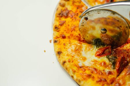 Cutting famous Neapolitan pizza based on buffalo mozzarella and tomatoes with a pizza cutter, italian cuisineの写真素材