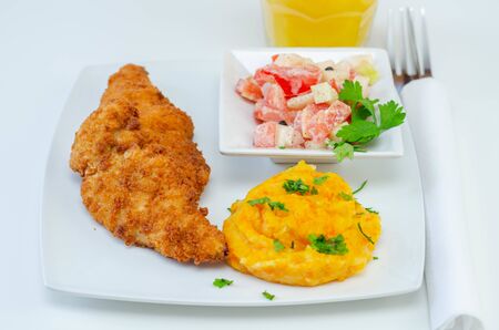 Breaded and herbed chicken breast fillet served with mashed carrots with potatoes  and  tomato salad with onions, tasty foodの写真素材