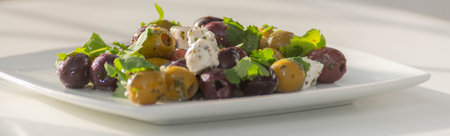 Fresh Greek salad based on green and black olives with pieces of white feta cheese and parsley, traditional Mediterranean cuisineの写真素材