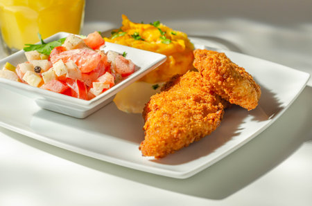 Breaded and herbed chicken breast fillet served with mashed carrots with potatoes  and  tomato salad with onions, tasty foodの写真素材