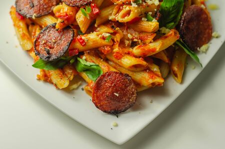 Pennette pasta in a spicy tomato sauce with sliced pepperoni, mozzarella, and mature cheddar cheeses, Italian foodの写真素材