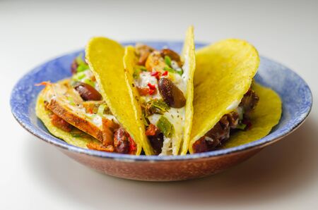 Mexican tacos shells with chicken and red kidney beans, onion,  red and green peppers, and salsa sauce, Latin foodの写真素材