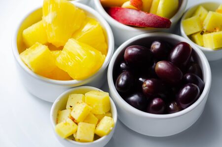 Various set fruits, pineapple, apple, grapes with matured cheddar cheese in bowls, healthy snackの写真素材