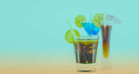 Three different colorful cocktails with lemon and ice cubes, refreshing alcoholic drinksの写真素材