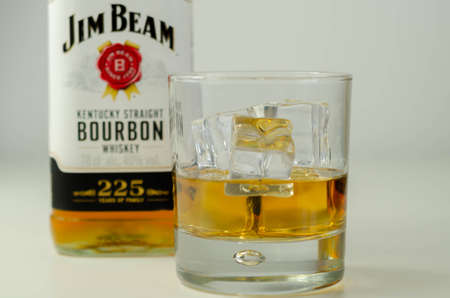 LONDON, UNITED KINGDOM - AUGUST 04, 2020 Straight bourbon whiskey by Jim Beam in a whiskey glass and a bottle commemorating 225 years of the Jim Beam familyのeditorial素材