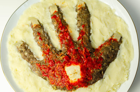 Roasted minced meat formed in the shape of a hand, topped with a tomato and pepper sauce, a creative...
