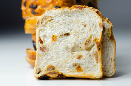 Fruit loaf with sultanas and orange flavored pieces on the white background, traditional fruit bread
