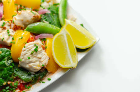 Cooked chicken breast pieces with peppers, sugar snap peas, and baby leaf spinach in a spicy sweet and sour sauce with fragrant rice, diet mealの写真素材