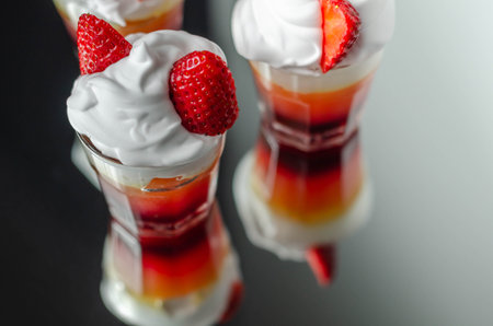 Colorful layered shots of drinks based on vodka, grenadine and orange juice decorated with whipped cream and pieces of strawberry in the shape of bunny ears, easter shotsの写真素材