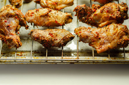 Raw chicken wings with a rendang style rub made with chilli and garlic on the grill tray, Asian food