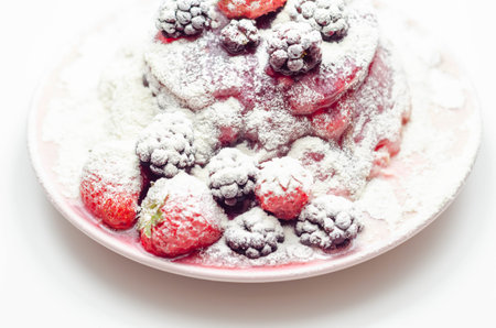 Pancakes stack with strawberries, blueberries, and blackberries, topped with sauce and sprinkled with powdered sugar, sweet breakfastの写真素材