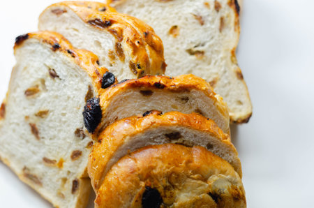 Fruit loaf with sultanas and orange flavored pieces on the white background, traditional fruit bread