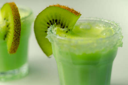 Fruit shot drink based on alcohol, liqueur and cream, decorated with green sugar crystals and a slice of fresh kiwi, exotic cocktailの写真素材