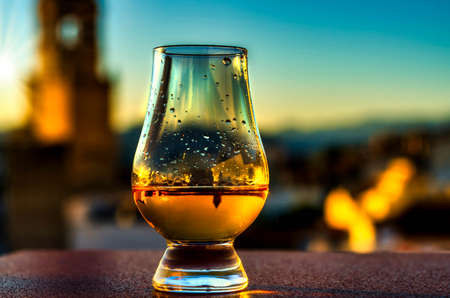 Expensive single malt whiskey in the rays of the setting sun, in the background a picturesque Spanish town with a church tower, relax with unique whiskeyの素材 [FY310168729829]