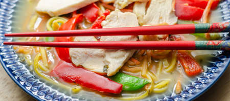 Chicken broth with ginger and black fungus mushrooms, high protein wheat noodles, sliced steamed chicken breast, julienne carrots, red peppers, and sugar snap peas, ramenの写真素材