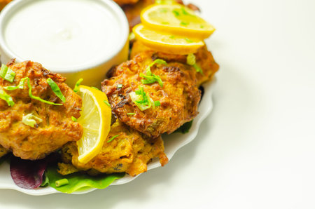 Delicious onion bhaji fritters served on ceramic plate with white dip, anglo-Indian cuisine