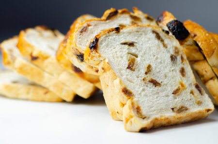 Fruit loaf with sultanas and orange flavored pieces on the white background, traditional fruit bread