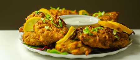 Delicious onion bhaji fritters served on ceramic plate with white dip, anglo-Indian cuisineの写真素材