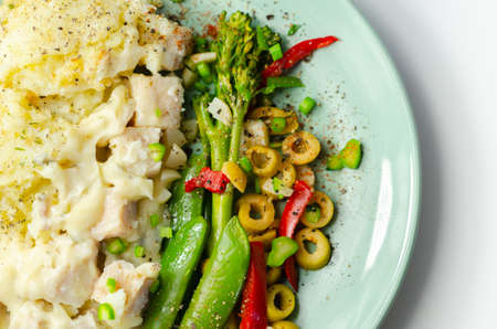 Tender pieces of smoked haddock and pollock in a creamy cheese sauce sat beneath buttery mash served with vegetables, classic English mealの写真素材