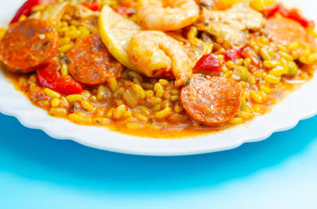 Delicious paella, cooked risotto rice with chicken thigh, king prawns, tomatoes and  chorizo, traditional Spanish mealの写真素材