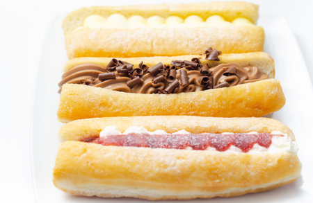 Mixed finger donuts filling chocolate, custard, jam and whipped cream, eclairs in different flavors,...
