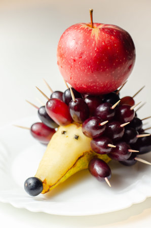Fruit hedgehog, red grapes, juicy pear and red apple, creative way of serving fruit, funny foodの写真素材