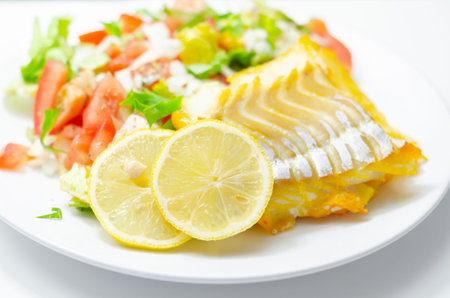Smoked haddock fillet served with a fresh salad consisting of lettuce, tomatoes and onion, healthy...