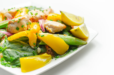Cooked chicken breast pieces with peppers, sugar snap peas, and baby leaf spinach in a spicy sweet and sour sauce with fragrant rice, diet mealの写真素材