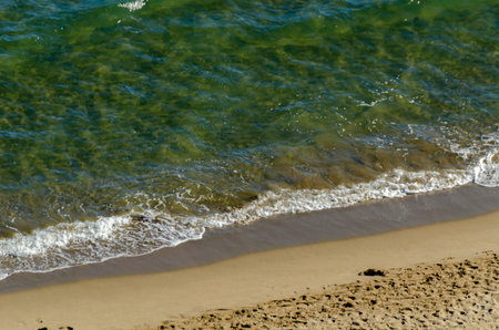 Top view on the sandy beach and turquoise mediterranean sea, beautiful waves and footprints on the...
