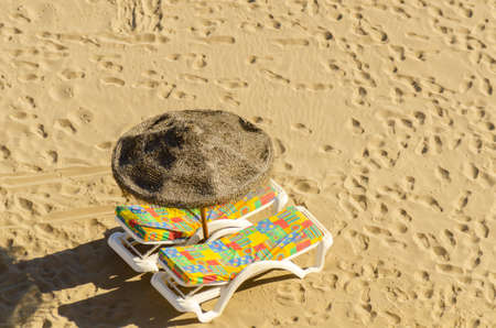 Beautiful sandy beach with palm tree umbrellas and sun loungers, sunny holidaysの写真素材