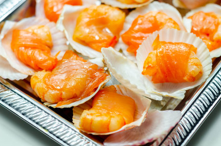 Warm water prawns wrapped in Scottish salmon cured with sea salt and demerara sugar smoked over oak, peat and cherrywood chips served in the natural scallop shells, exclusive foodの写真素材