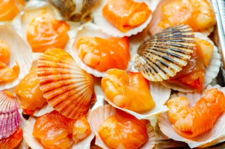 Warm water prawns wrapped in Scottish salmon cured with sea salt and demerara sugar smoked over oak, peat and cherrywood chips served in the natural scallop shells, exclusive foodの写真素材