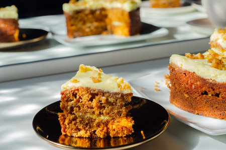 Sliced carrot cake filled and topped with cream cheese buttercream and decorated with walnuts,...