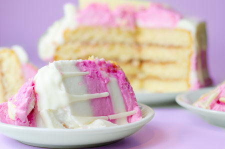 Moist madeira sponge, layered with plum and raspberry jam, coated and topped with white and pink colour frostings, decorated with white chocolate decorations, birthday cakeの写真素材
