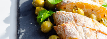 Baguette stuffed with olives, cut with fresh green olives and parsley, served on a stone plate, healthy appetizerの写真素材