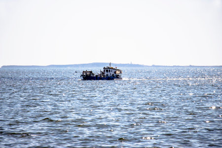 The fishing boat sails to the shore under the rays of the sun