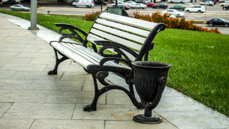 A bench and an urn near a park path and a lawn in the springの写真素材