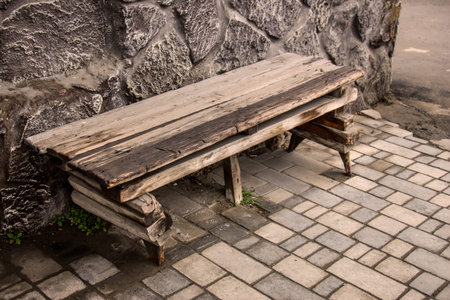 Bench made of wood on the edge of a wall of chopped stones