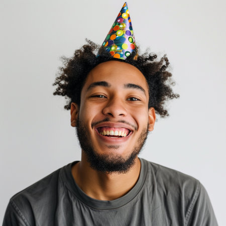 Portrait of a happy african american man with birthday hat on grey backgroundの素材