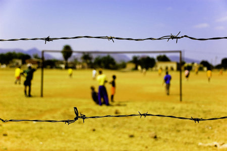 Playing Soccer on a Field Surrounded by Barbed Wire in South Africaの写真素材