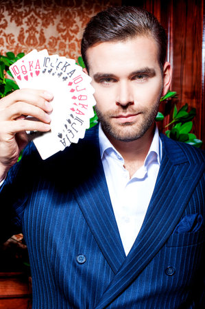 Handsome man in suit poses with cardsの写真素材