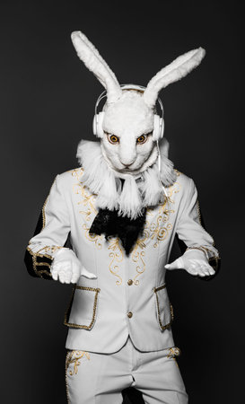 Actor posing in white rabbit suit with earphones on  black background