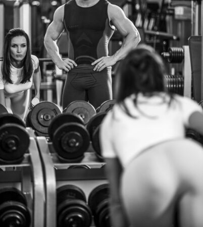 beautiful woman in gym with personal trainerの写真素材